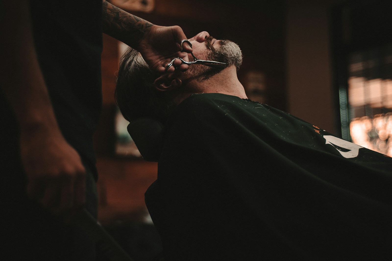 Barbeiro fazendo o acabamento do corte de um cliente