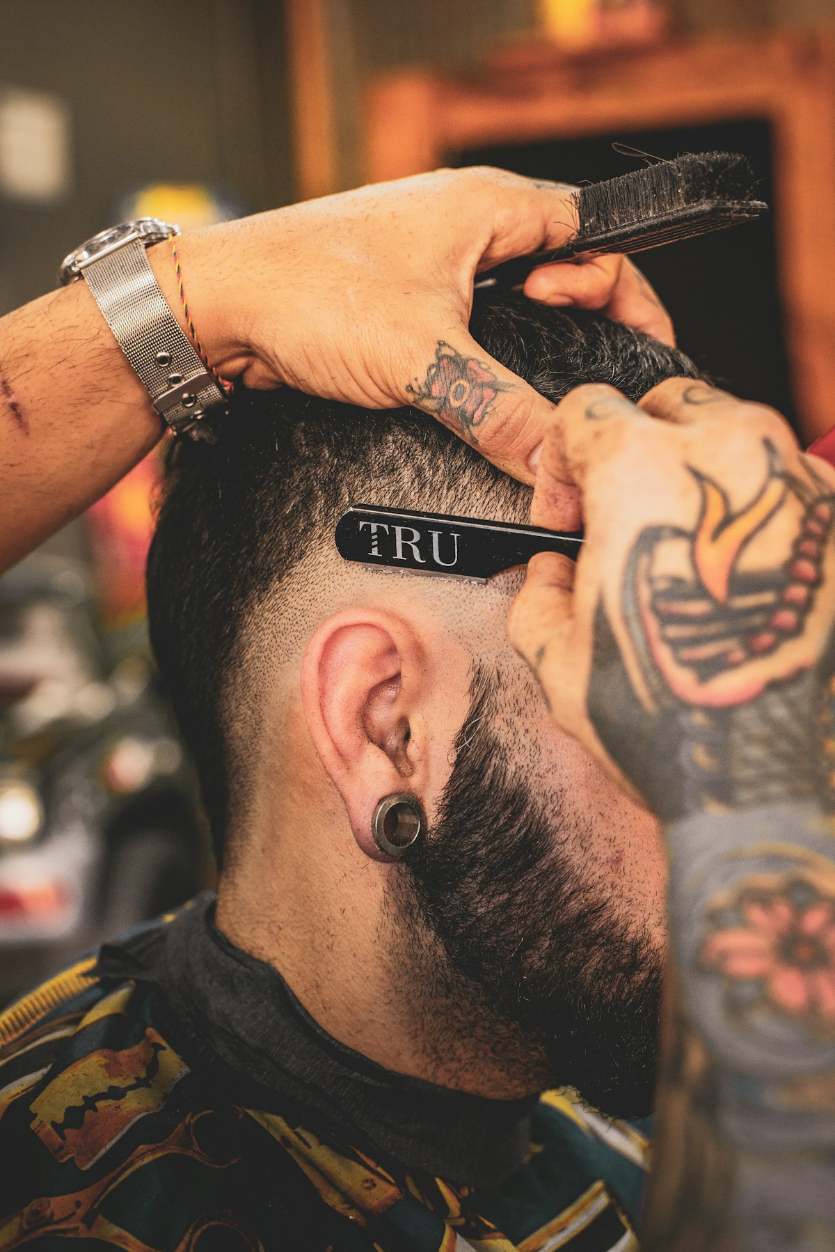 Barbeiro trabalhando próximo ao rosto de um cliente